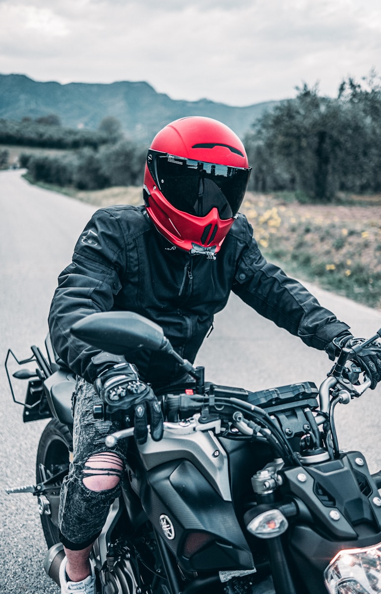 a man with motorcycle safety gear riding a motorcycle down a country road